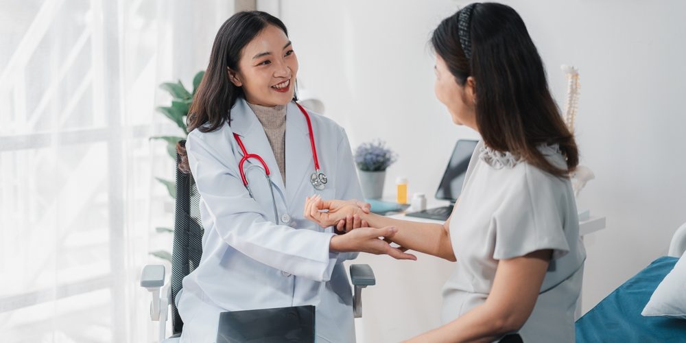 Young Asian Doctor checks the pulse of her patient