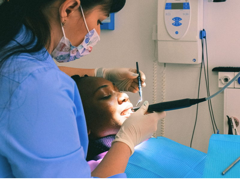A dentist meets with a patient during an appointment, reviewing oral health and discussing care recommendations.